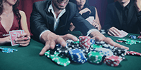 Un jugador de póker recogiendo varias pilas de fichas tras una partida.